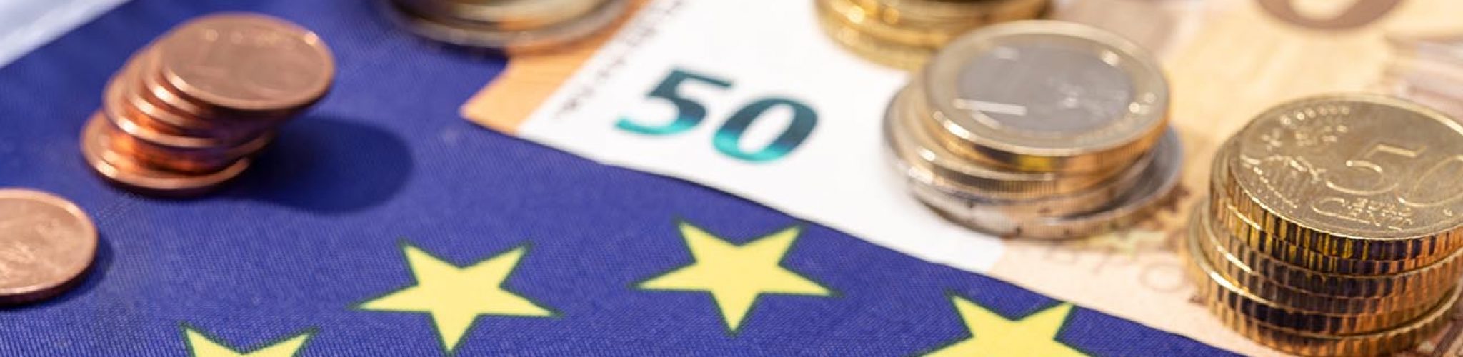 European Union financial stimulus on coronavirus Covid-19 pandemic concept. European Union flag with euro bills and coins